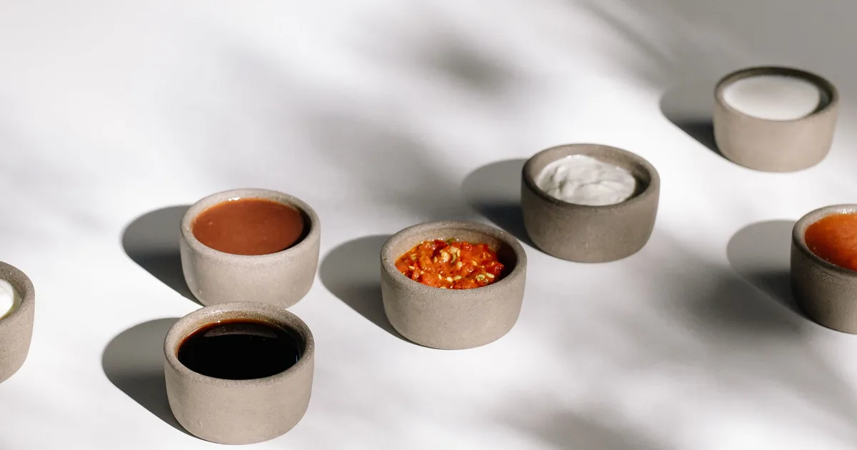 An array of small ceramic bowls of dipping sauces — guide to Dave's Hot Chicken sauce and dippers