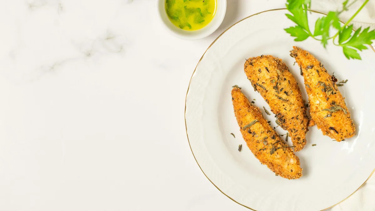 Crispy fried chicken tenders on a white plate — protein, carbs and fat in Dave's Hot Chicken