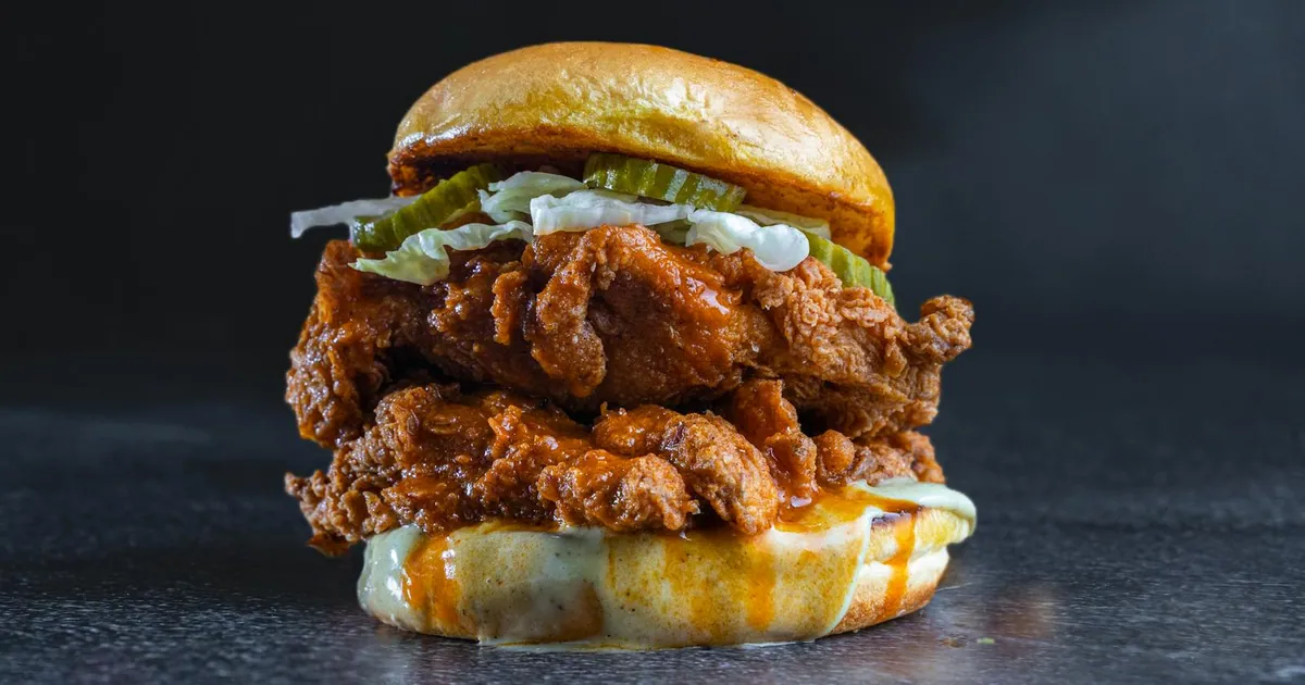 Nashville-style hot chicken slider with pickles on a dark background — Dave's Hot Chicken spice levels guide